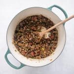 Browned sausage and pork returned to the pot with sautéed vegetables.
