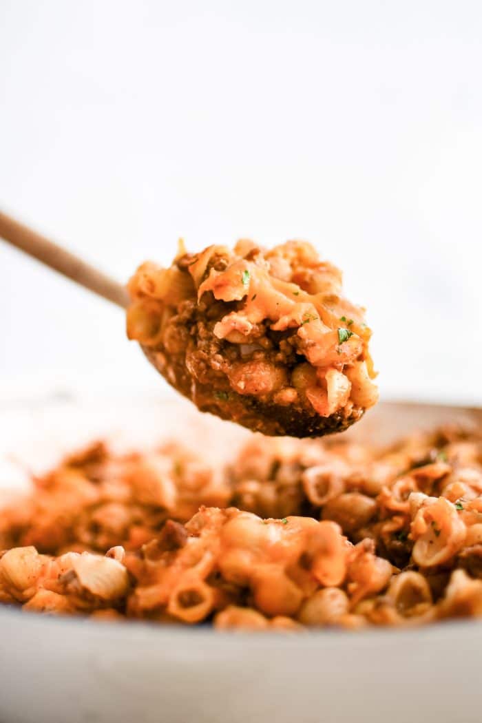 A wooden serving spoon loaded with cooked sloppy joe casserole.