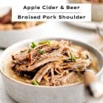 A comforting bowl of creamy mashed potatoes topped with succulent, fork-tender braised pork shoulder and garnished with fresh herbs for a rustic, hearty meal.