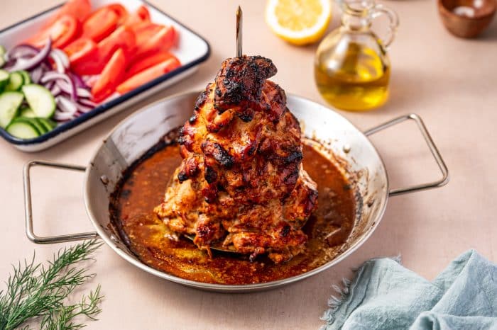 Tender slow-cooked chicken gyro on a vertical spit with crispy charred edges.