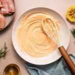 Mixing Greek yogurt marinade with olive oil, lemon juice, oregano, paprika, and salt in a large bowl.
