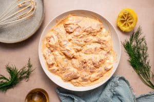 Marinated chicken thighs thoroughly coated in creamy yogurt marinade, placed in a bowl.