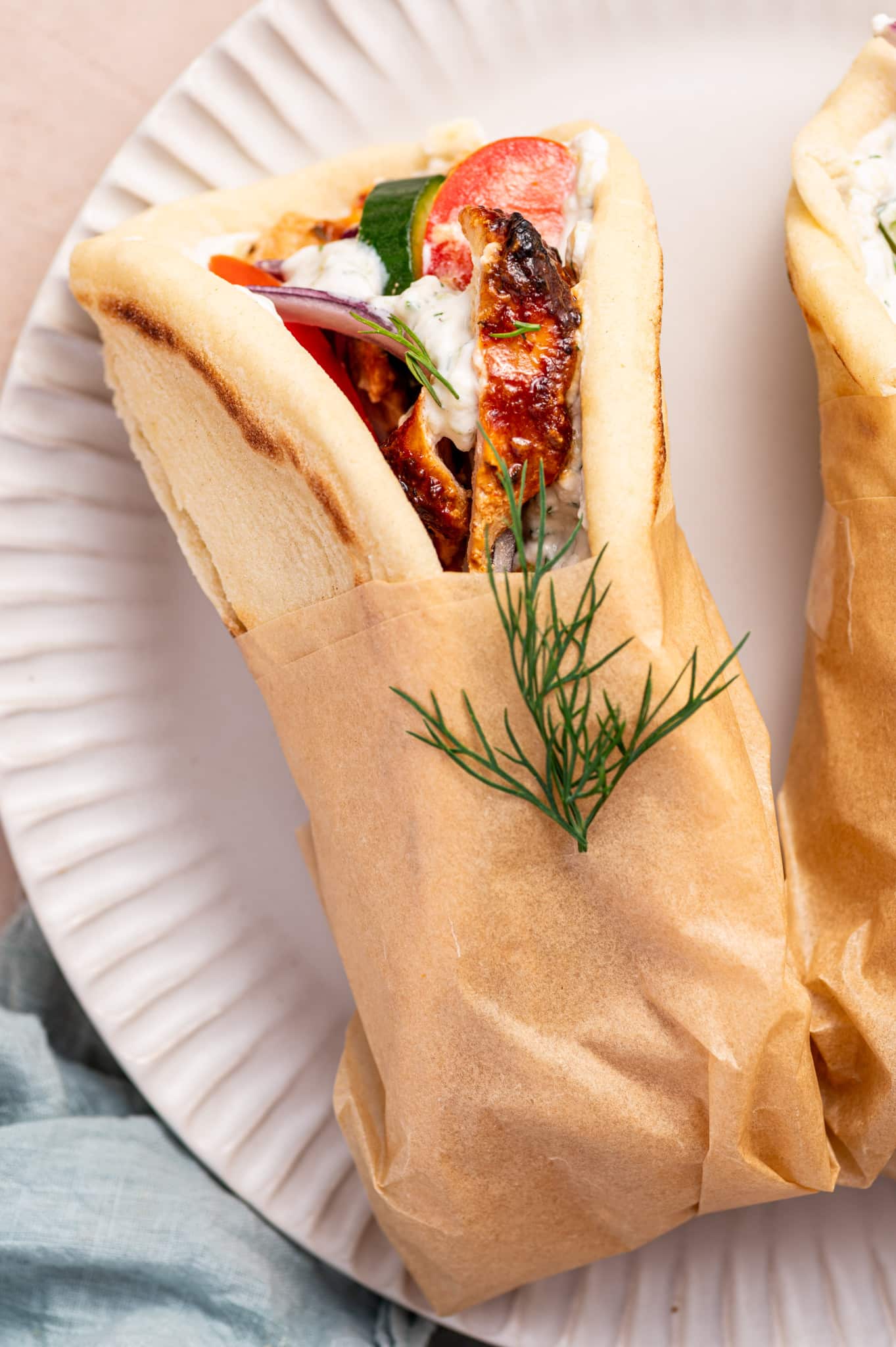 A wrapped chicken gyro pita filled with chicken gyro meat, tzatziki sauce, cucumber, tomatoes, and red onion.