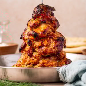 Tender slow-cooked chicken gyro on a vertical spit with crispy charred edges.