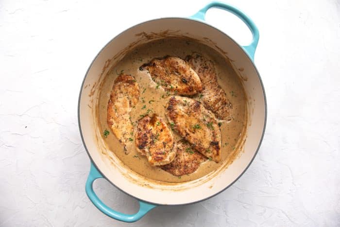 Golden pan-seared chicken cutlets in a turquoise-handled Dutch oven, simmering in creamy ranch gravy.