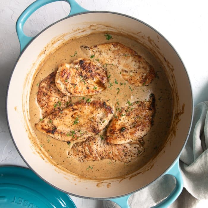 Golden pan-seared chicken cutlets in a turquoise-handled Dutch oven, simmering in creamy ranch gravy.