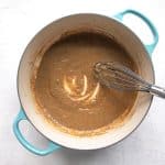 A rich brown gravy simmering in a round turquoise-colored Dutch oven.