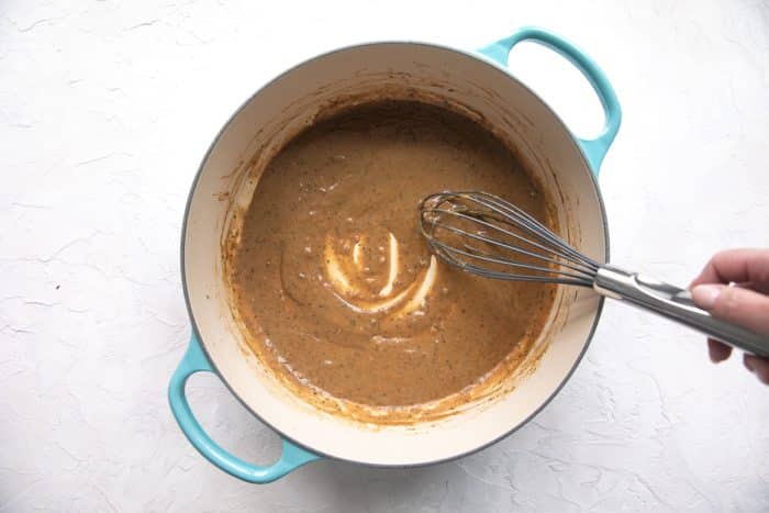 A rich brown gravy simmering in a round turquoise-colored Dutch oven.