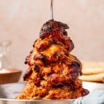 Text "How to Make Greek Chicken Gyros" over an image of tender slow-cooked chicken gyro on a vertical spit with crispy charred edges.