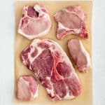 The five types of pork chops (rib chop, boneless chop, sirloin chop, shoulder chop, and loin chop) on top of brown butcher paper.