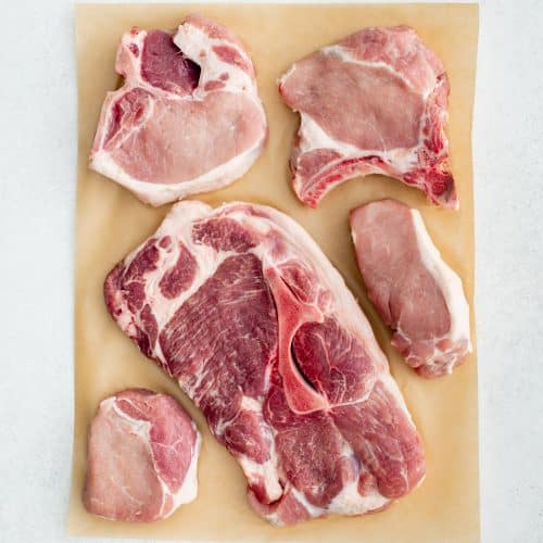 The five types of pork chops (rib chop, boneless chop, sirloin chop, shoulder chop, and loin chop) on top of brown butcher paper.