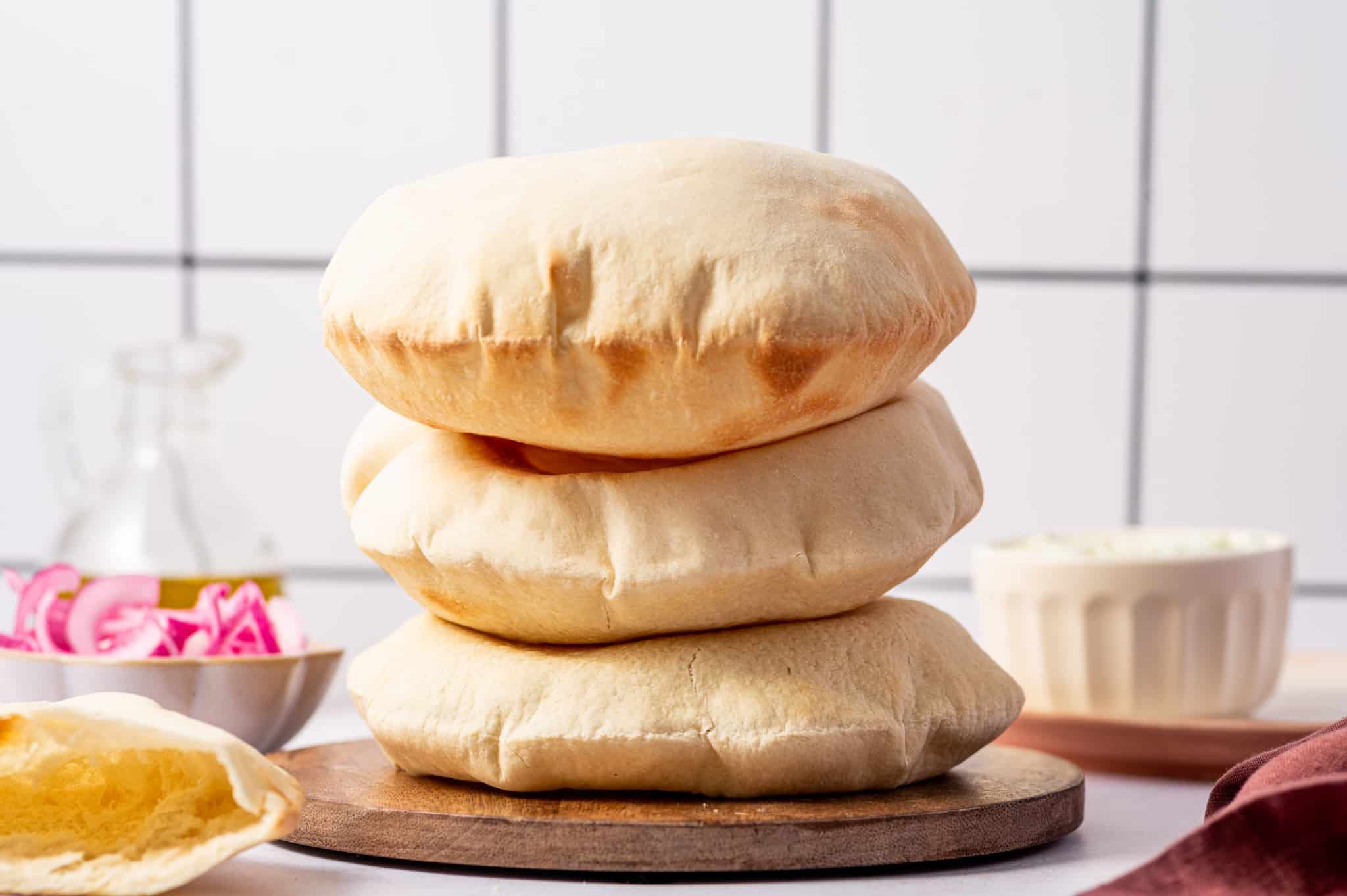 Three puffed up pita bread stacked on top of each other warm and fresh out of the oven.