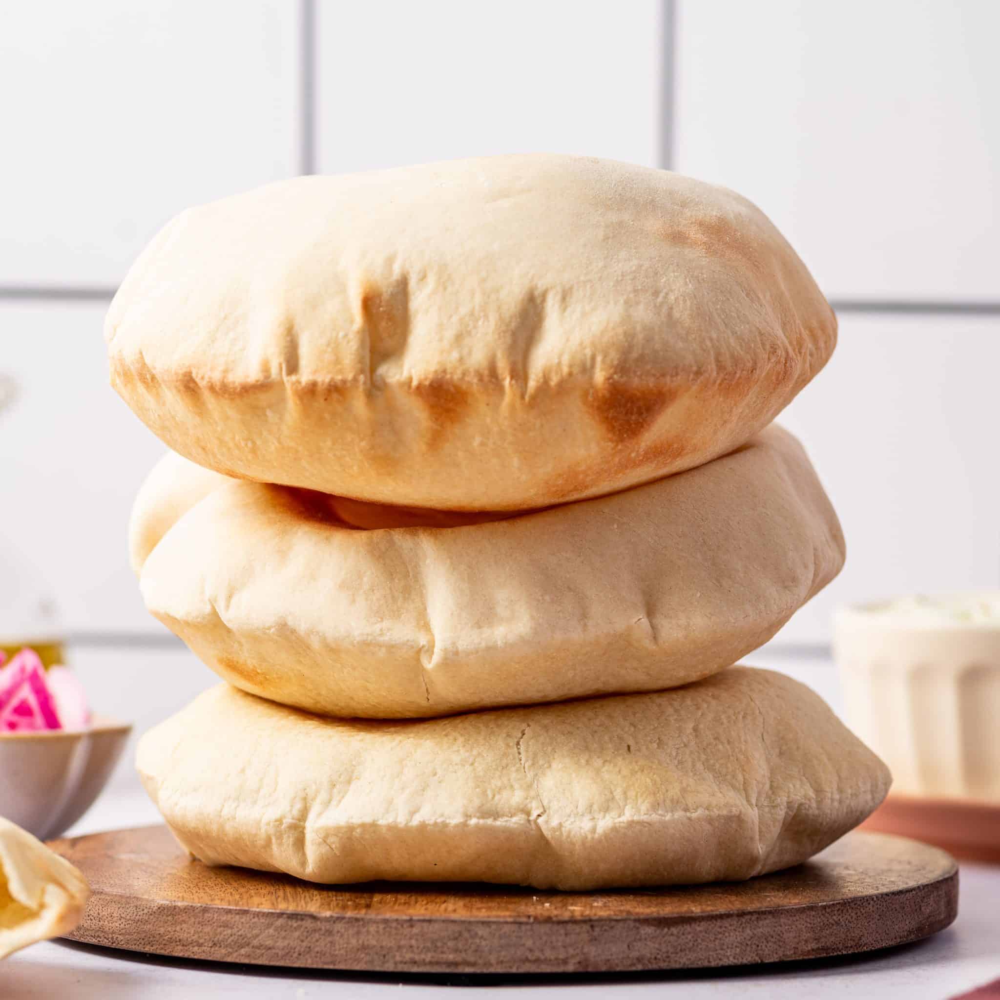 Three puffed up pita bread stacked on top of each other warm and fresh out of the oven.