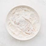 A piece of chicken freshly dredged in the flour mixture.