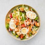A finished restaurant-style house salad served with ranch dressing and an optional sprinkle of extra croutons for added crunch and flavor.