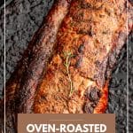 A golden-brown, oven-roasted pork loin sits in a large cast iron skillet. The roast is seared and glistening, indicating it's just come out of the oven and is ready to rest before slicing.