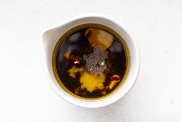 top-down shot showing olive oil, balsamic vinegar, Dijon mustard, honey, garlic, salt, and pepper before whisking.