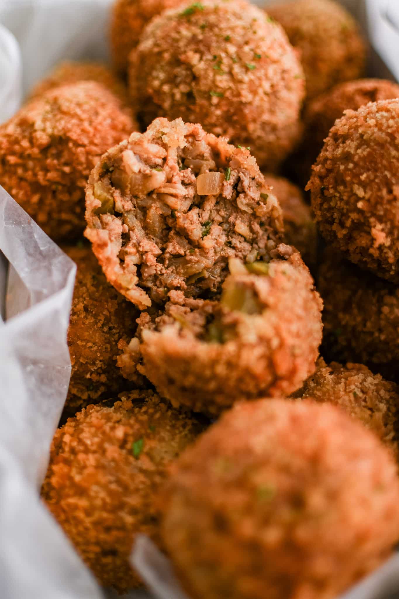 One boudin ball torn in half reveals its savory pork and rice filling, surrounded by a perfectly crispy coating