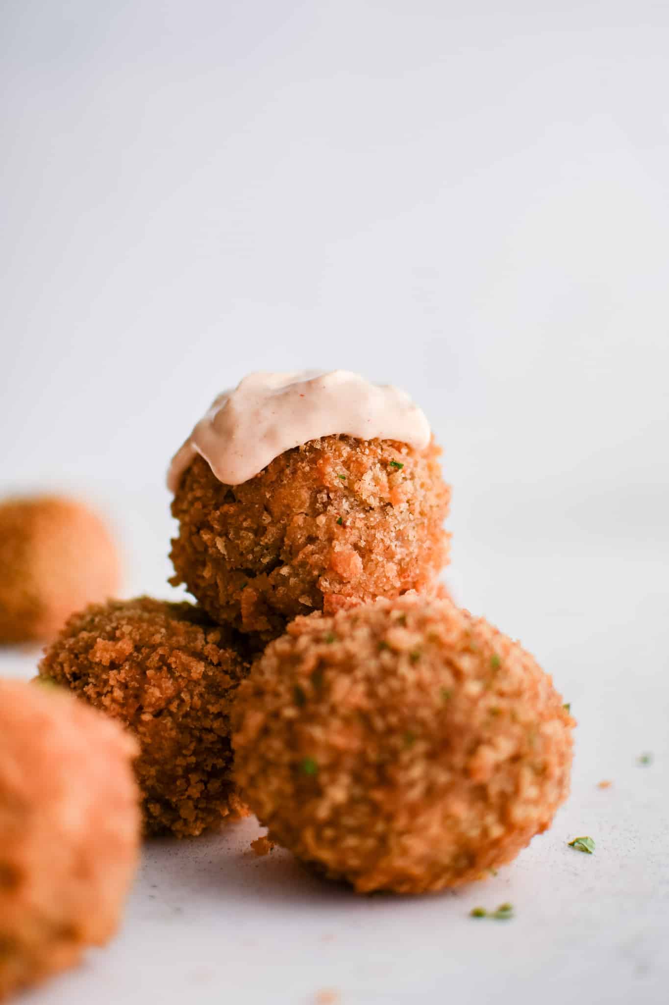 A boudin ball sitting atop a small stack, crowned with a dollop of remoulade sauce.