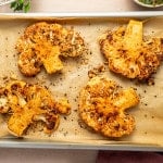 Golden roasted cauliflower steaks fresh from the oven on a parchment-lined baking sheet.