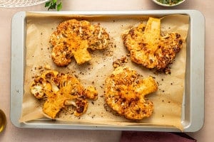 Golden roasted cauliflower steaks fresh from the oven on a parchment-lined baking sheet.