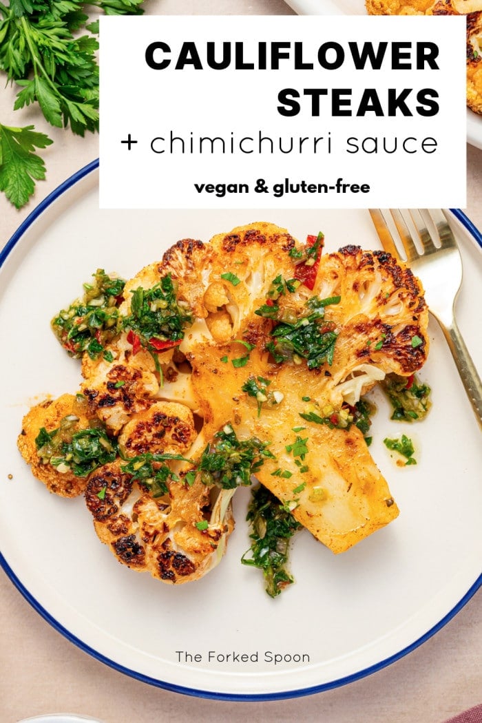 Overhead view of roasted cauliflower steak topped with chimichurri on a white plate with bold text overlay reading “Cauliflower Steaks + chimichurri sauce.”