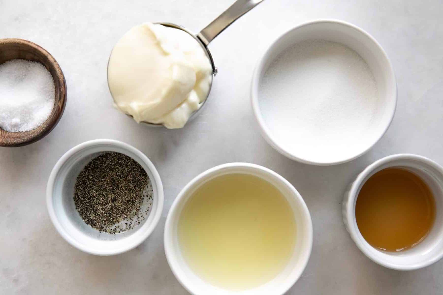 Coleslaw ingredients - pepper, mayonnaise, lemon juice, apple cider vinegar, and sugar.