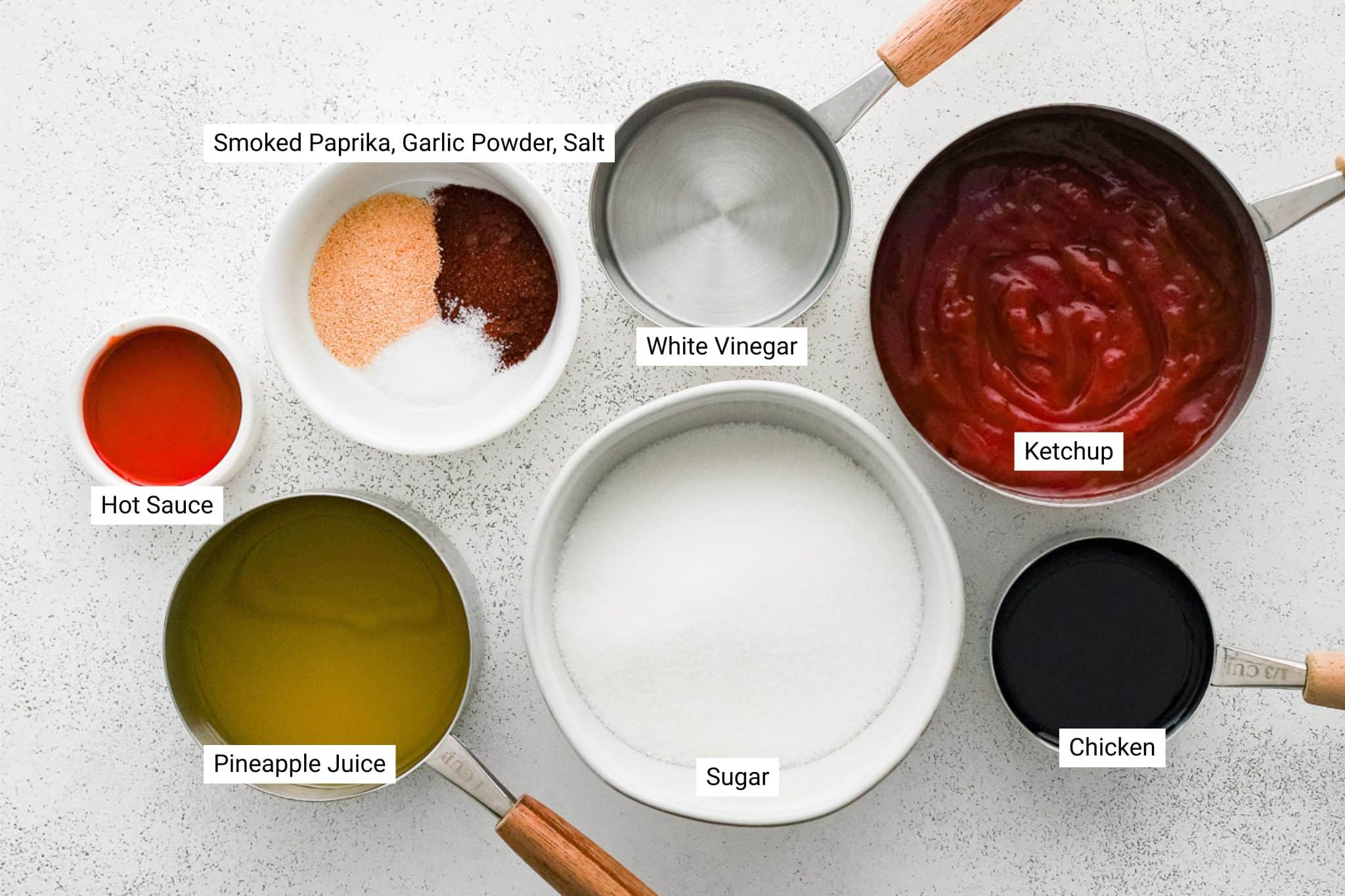 Overhead view of measured ingredients including ketchup, sugar, vinegar, pineapple juice, hot sauce, soy sauce, and spices, each clearly labeled.
