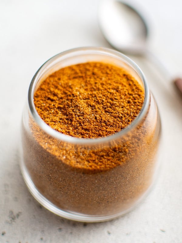 Close-up of homemade sazón seasoning stored in a small glass spice jar