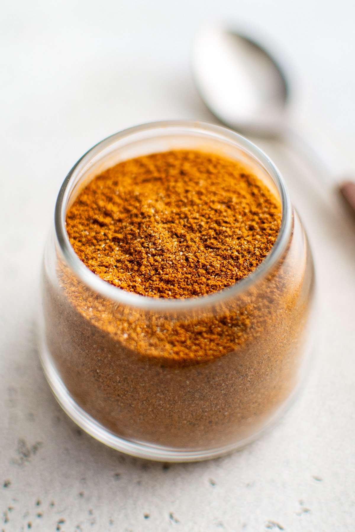 Close-up of homemade sazón seasoning stored in a small glass spice jar