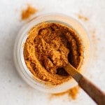 Overhead shot of sazón seasoning in a jar with a small spoon