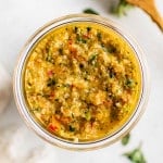 Bright, fresh sofrito packed into a glass jar, showing the texture and color of the final product from above.