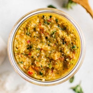 Bright, fresh sofrito packed into a glass jar, showing the texture and color of the final product from above.