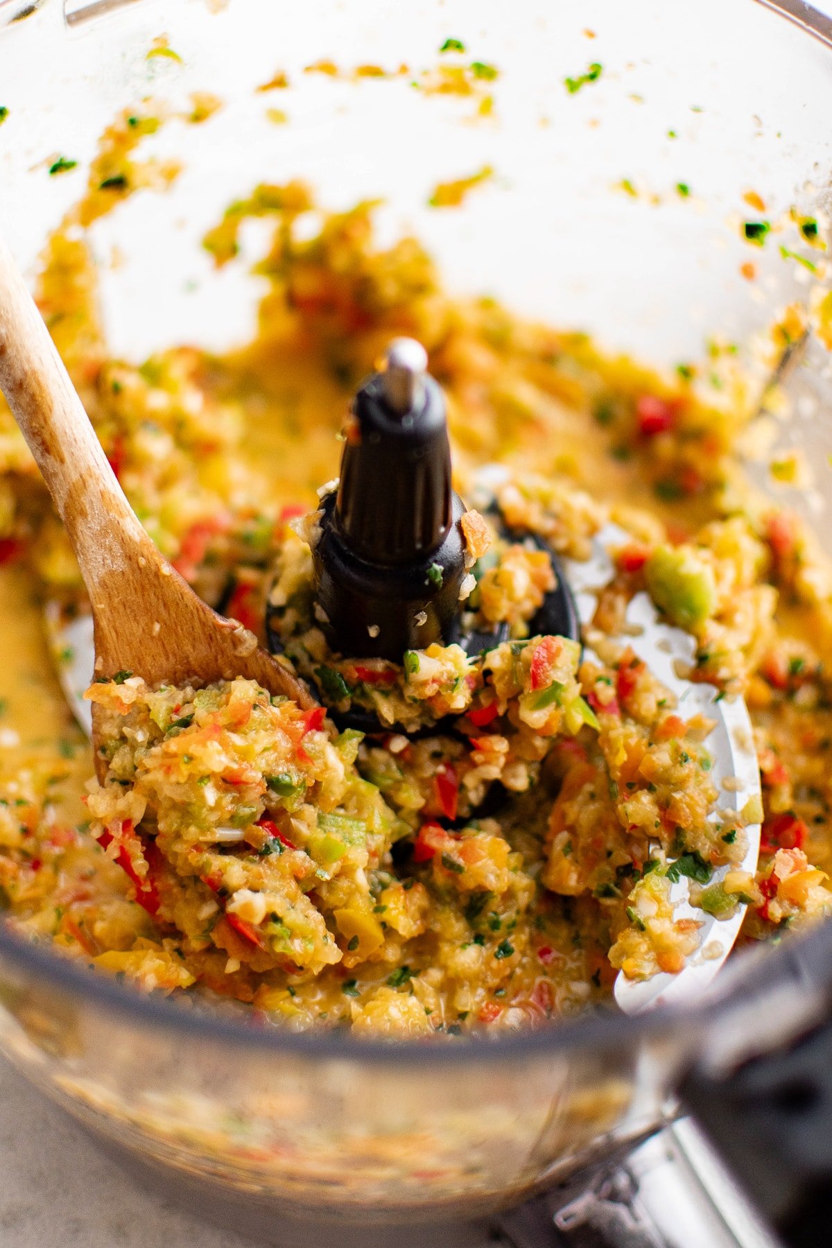 Wooden spoon scooping fresh sofrito out of a food processor