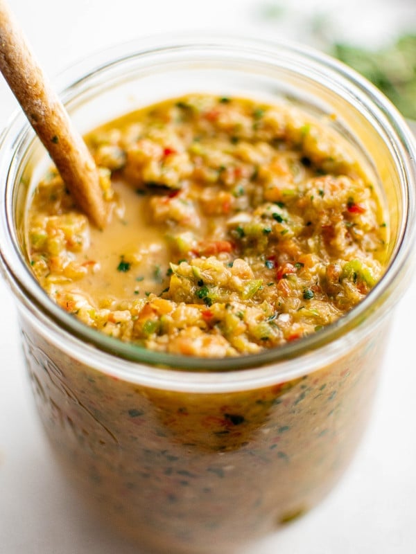 Jar filled with vibrant homemade sofrito with a wooden spoon resting inside