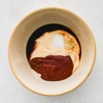 Bowl with mayonnaise, gochujang, garlic, soy sauce, sugar, and rice vinegar before mixing.