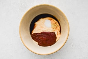 Bowl with mayonnaise, gochujang, garlic, soy sauce, sugar, and rice vinegar before mixing.