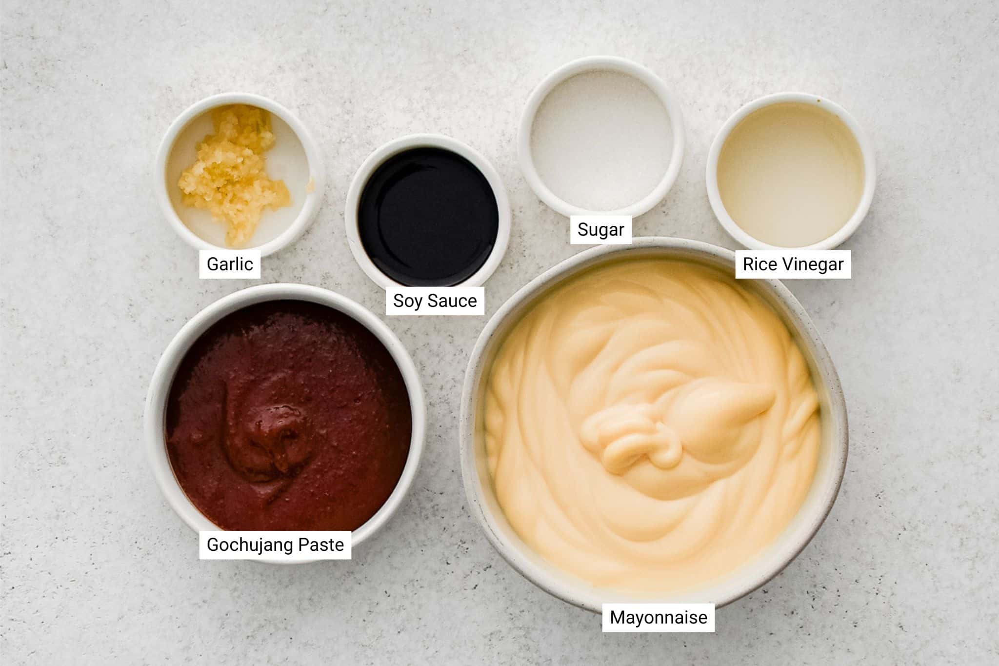 Small bowls labeled with ingredients: gochujang, mayonnaise, garlic, soy sauce, sugar, and rice vinegar.