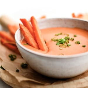 Close-up of sweet potato fries dipped in spicy mayo garnished with scallions.