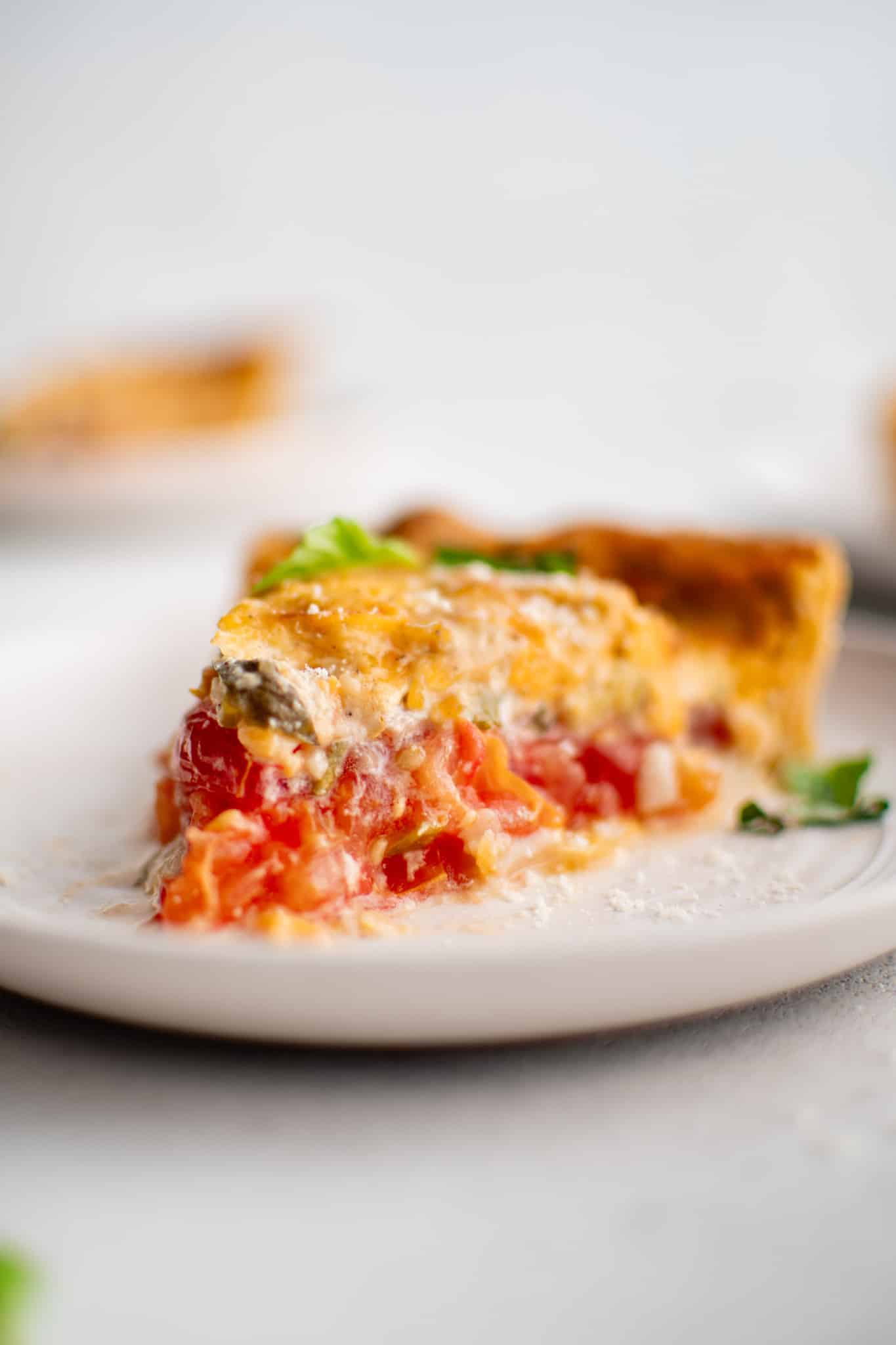 A creamy Southern tomato pie slice showcasing layers of fresh tomatoes, cheese, and herbs in a flaky crust
