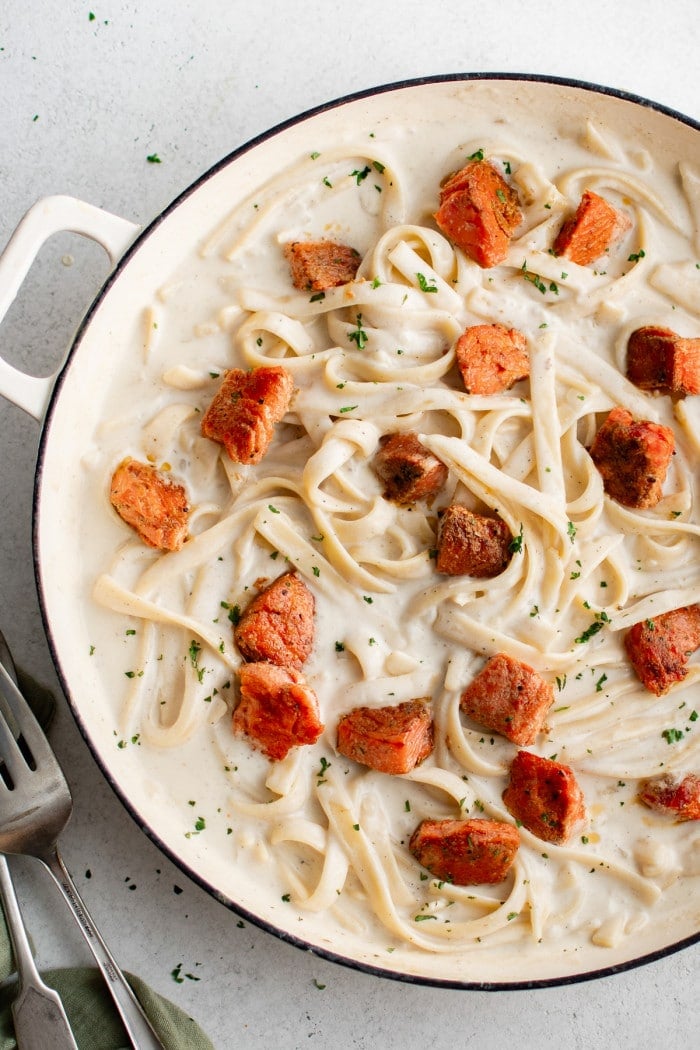Creamy fettuccini pasta topped with seared Cajun salmon and garnished with parsley.