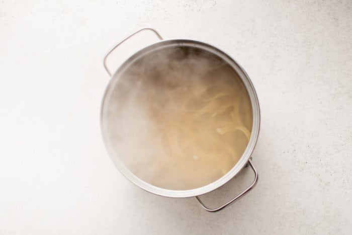 Fettuccini noodles boiling in a pot of salted water.