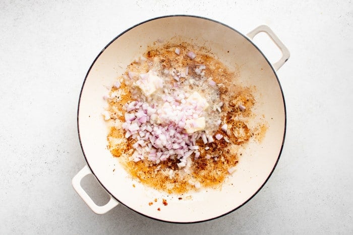 Chopped shallots cooking in butter in the same skillet that was used to cook the Cajun-seasoned salmon.