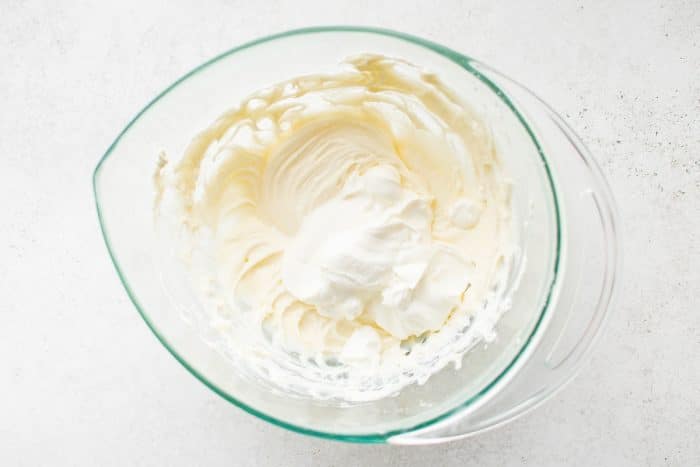 Cream cheese mixture with sour cream added in a glass bowl.