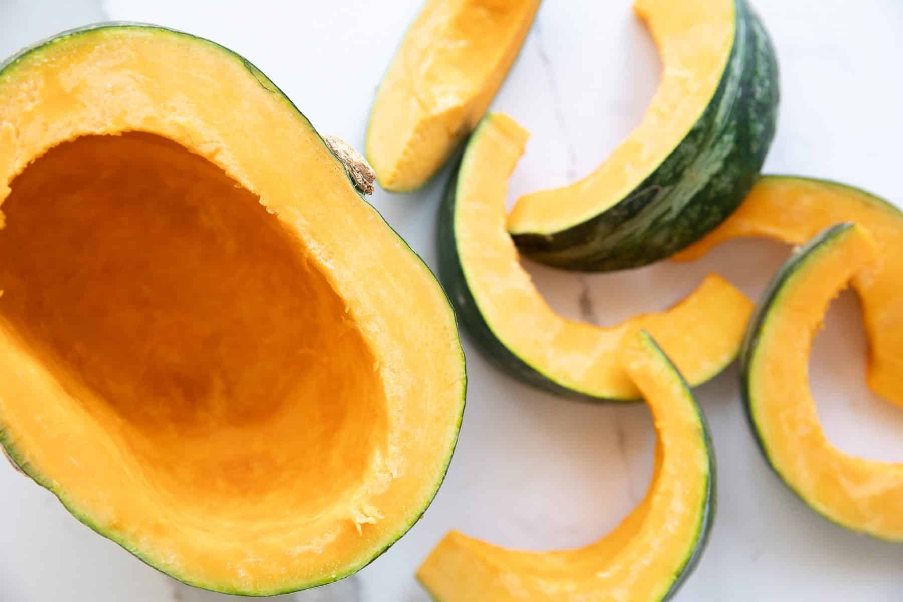 Kabocha squash cut in half, seeds removed, and one half cut into smaller half-moons.