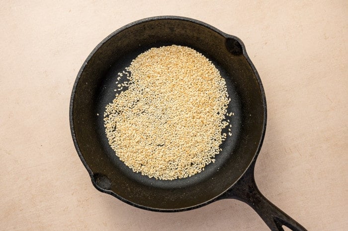 Toasting sesame seeds in a cast iron skillet for homemade za’atar seasoning.