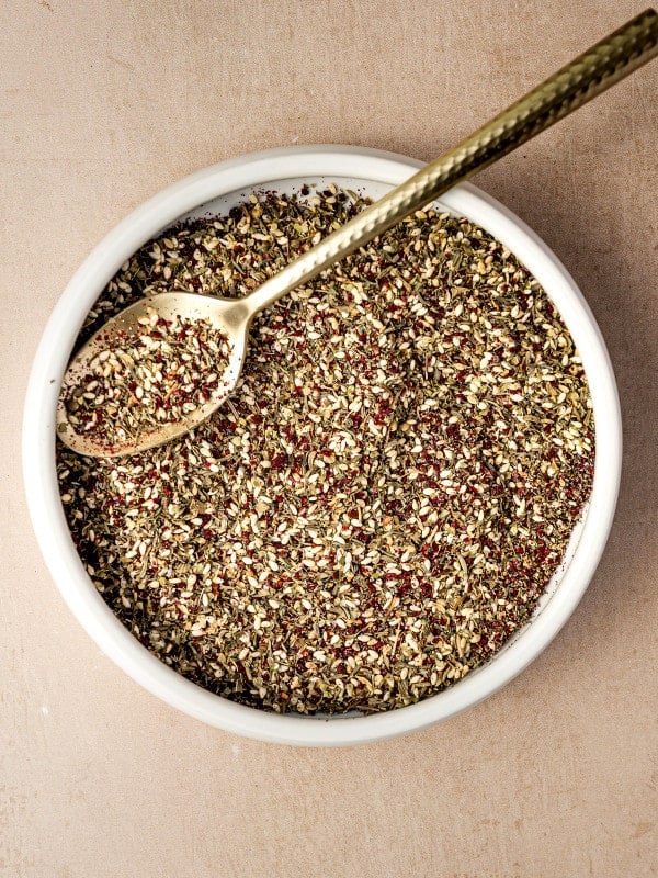 Overhead view of a bowl filled with za’atar spice blend and a gold spoon