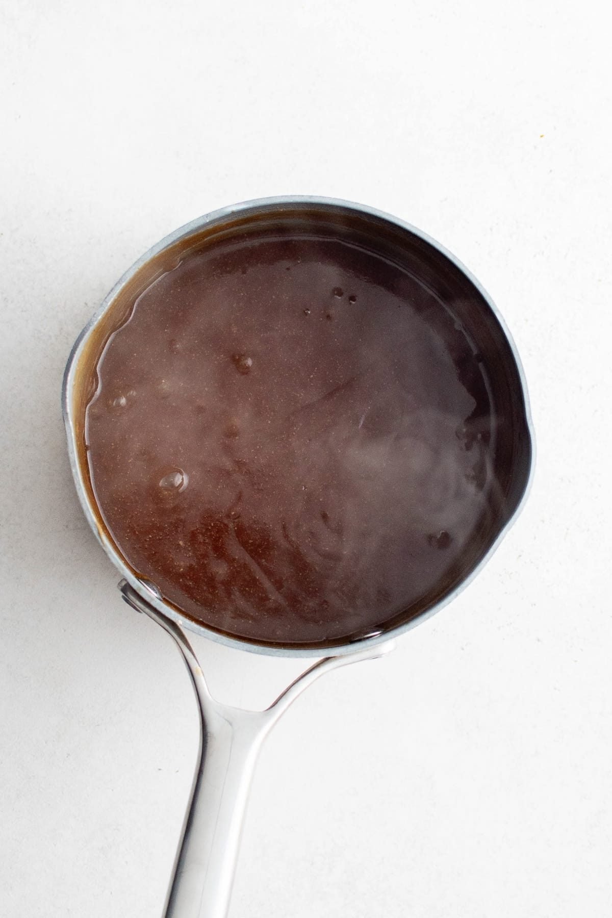 Thickened homemade Hawaiian sauce simmering in a small saucepan.