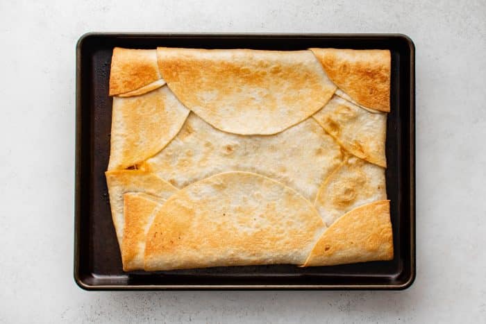 An overhead view of baked sheet pan quesadillas fresh from the oven, with the tortillas golden brown and crisp around the edges.