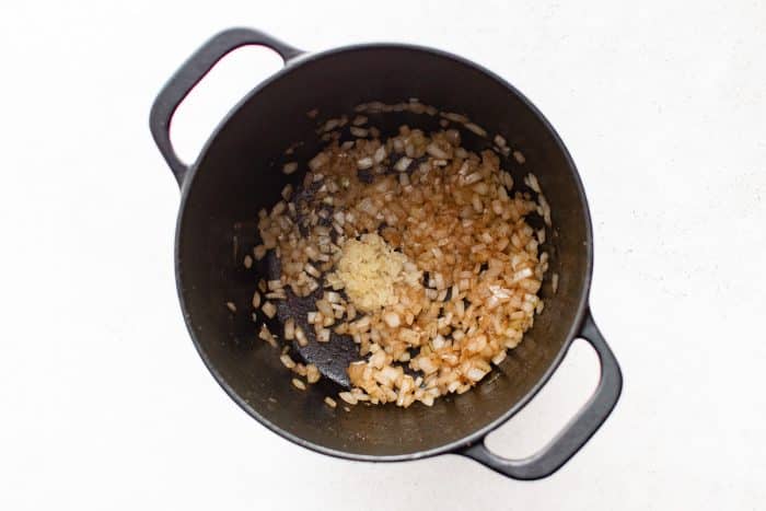 Minced garlic added to sautéed onions in a Dutch oven.